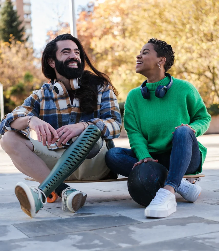 Man with prosthetic leg and friend sitting on skateboard